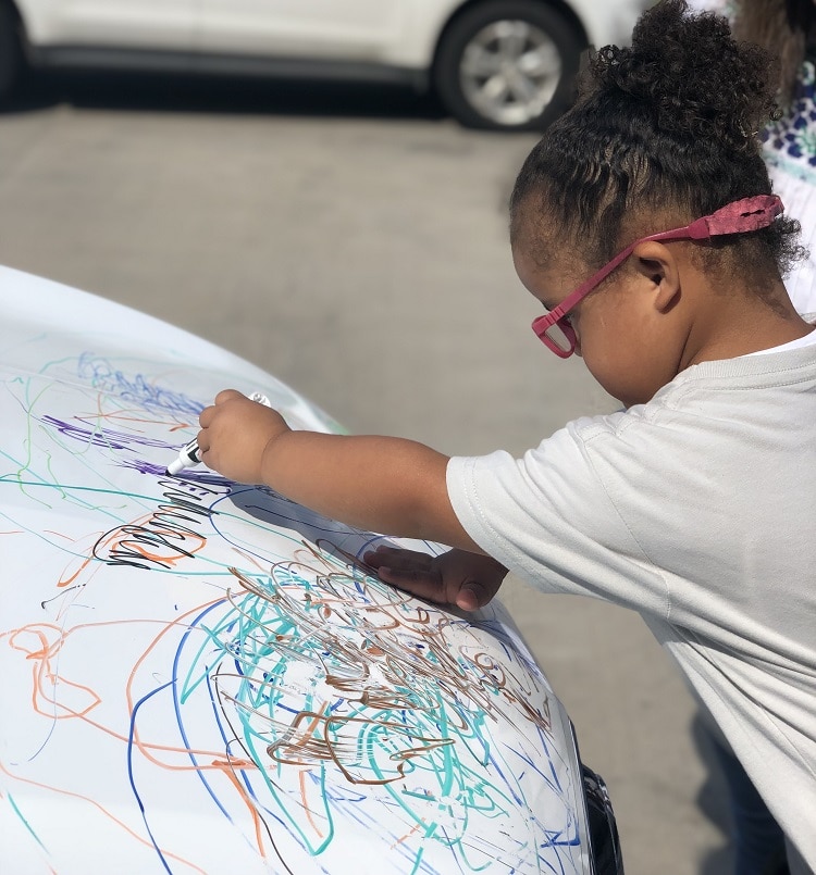 girl drawing on alto car hood