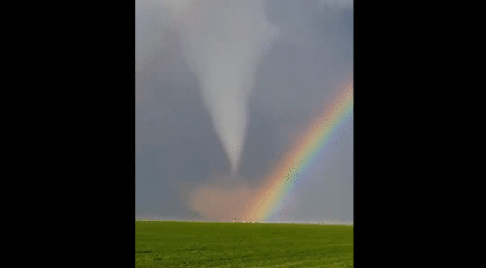 double rainbow in front of a tornado over a field of grass