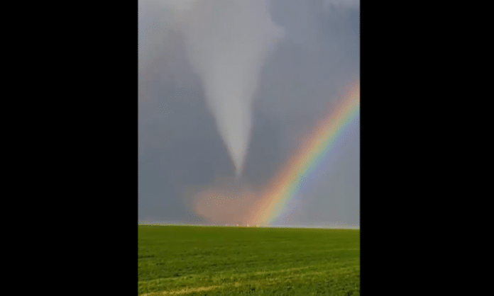 double rainbow in front of a tornado over a field of grass