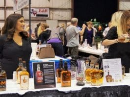 two women standing at a table providing alcohol tastings