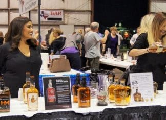 two women standing at a table providing alcohol tastings