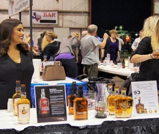 two women standing at a table providing alcohol tastings