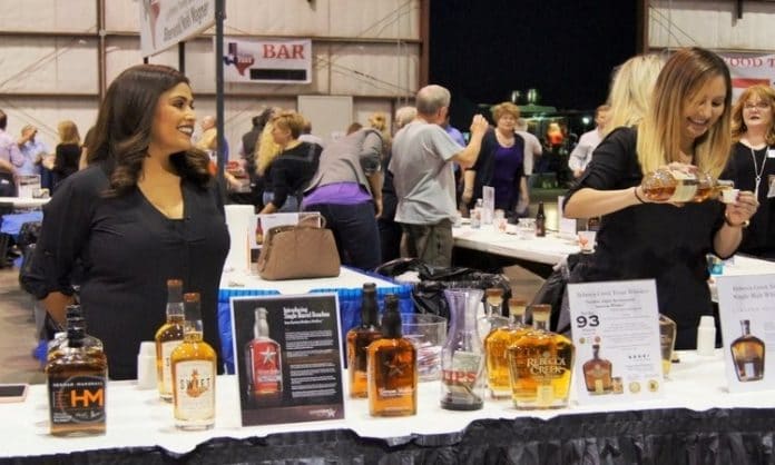 two women standing at a table providing alcohol tastings