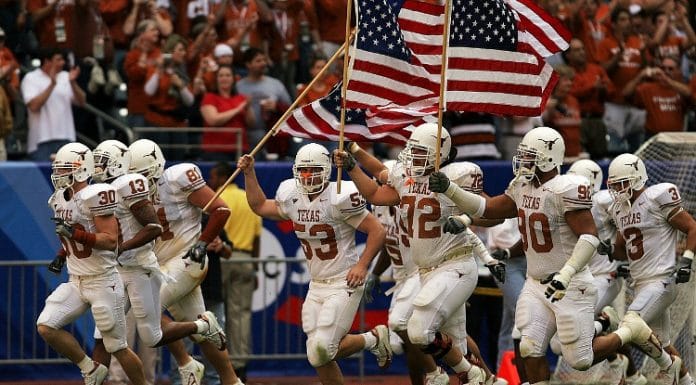 UT Austin football players on the field holding American flags