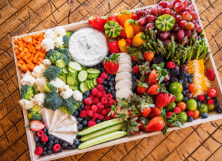 large tray charcuterie board filled with an array of fruits, vegetables, cheeses, and more