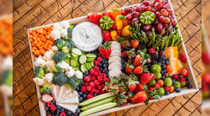 large tray charcuterie board filled with an array of fruits, vegetables, cheeses, and more