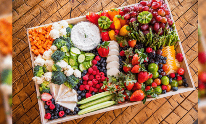 large tray charcuterie board filled with an array of fruits, vegetables, cheeses, and more