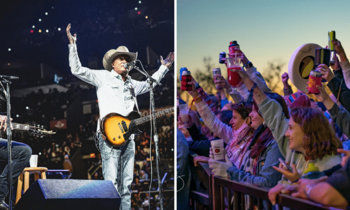 people in a crowd holding up theirs drinks to the stage and a man playing guitar on stage