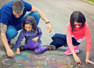 father and daughters making chalk art